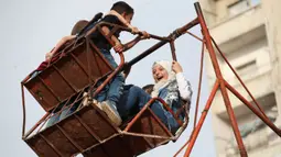 Anak-anak Suriah bermain di taman darurat selama perayaan Idul Fitri, hari libur Muslim yang dimulai pada akhir bulan puasa Ramadan, di Binnish di provinsi Idlib, Suriah barat laut yang dikuasai pemberontak, (26/5/2020). (AFP Photo/Omar Haj Kadour)