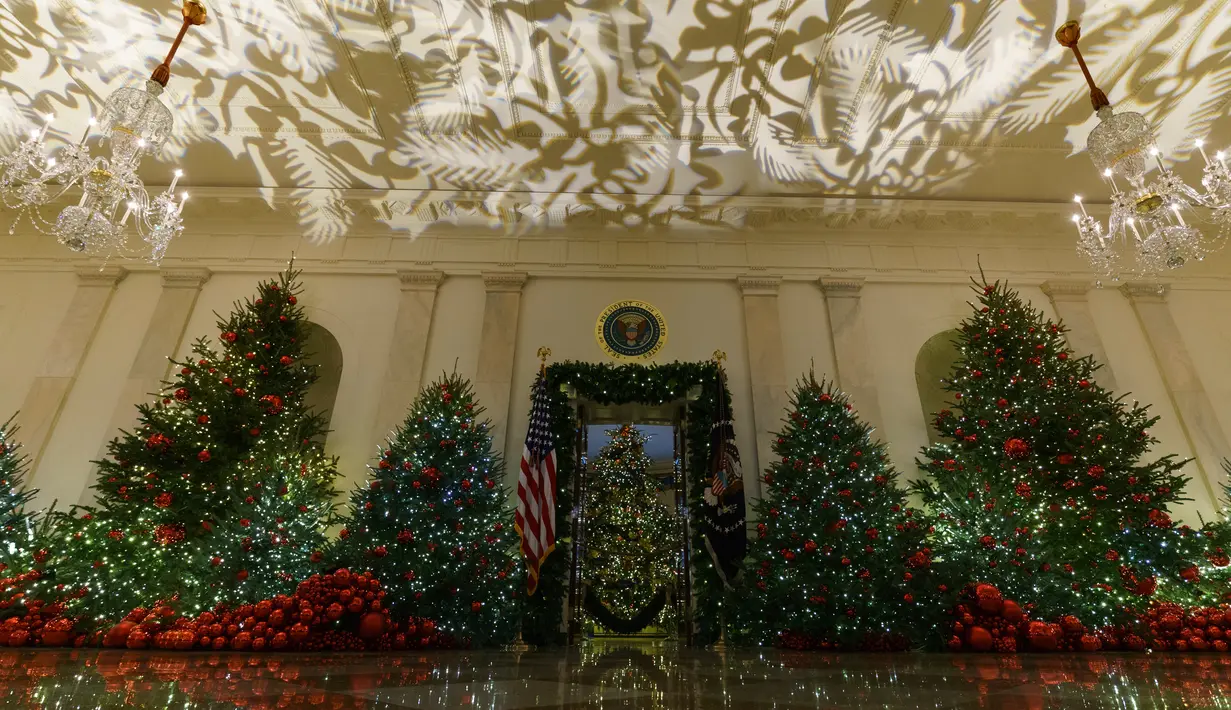 Ruangan The Grand Foyer dan Cross Hall dihiasi sejumlah pohon cemara yang didekorasi untuk perayaan Natal di Gedung Putih, Washington DC, Senin (26/11). Tema dekorasi yang diangkat tahun 2018 ini adalah 'American Treasures'. (AP/Carolyn Kaster)