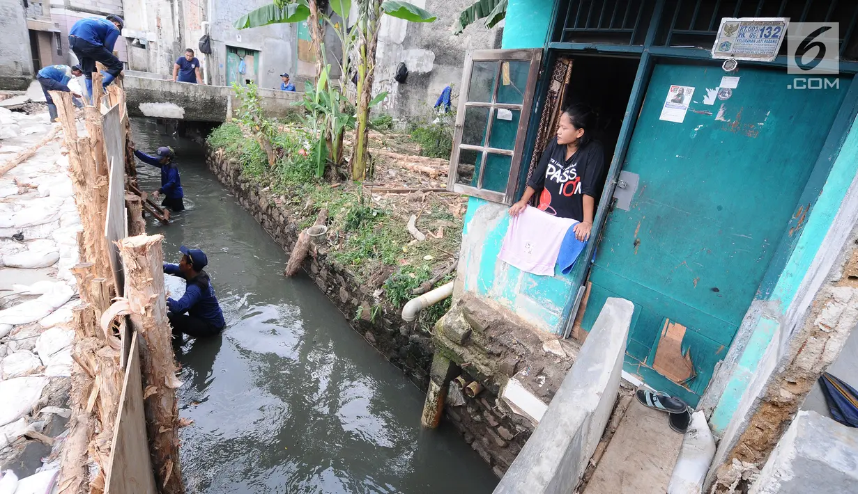 Warga melihat petugas Sudin Sumber Daya Air (SDA) memperbaiki tanggul jebol di kawasan Jati Padang, Pasar Minggu, Jakarta Selatan, Kamis (18/4). Tanggul kembali jebol akibat derasnya air kali Pulo akibat hujan deras yang melanda kawasan Jakarta pada 16 April 2019 lalu. (Liputan6.com/Herman Zakharia)