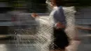 Seorang gadis berlari mendinginkan dirinya berlari di air mancur di sebuah taman di Moskow, Rusia, (3/8). Cuaca panas di Moskow terus berlanjut, dengan suhu diperkirakan mencapai 30 derajat Celcius (86 Fahrenheit). (AP Photo/Alexander Zemlianichenko)