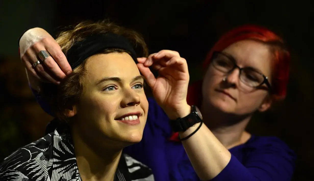 Seorang pegawai tampak merapikan patung salah satu member One Direction, Harry Styles, di museum lilin Madame Tussauds, London, Rabu (6/8/14). (AFP PHOTO/Carl COURT)