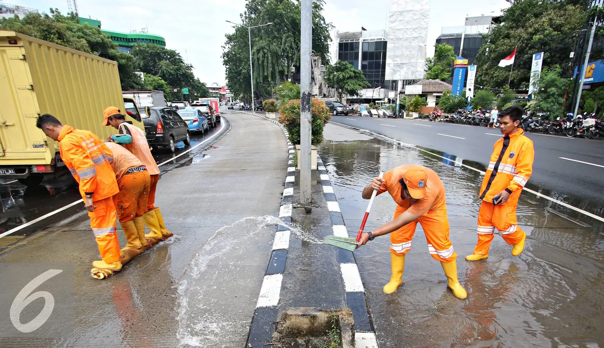 Semangat petugas membersihkan genangan air di Harmoni, Jakarta, Selasa (9/2). Buruknya sistem drainase membuat petugas terpaksa harus membersihkan genangan setiap kali hujan, meski dengan peralatan seadanya. (Liputan6.com/Immanuel Antonius)