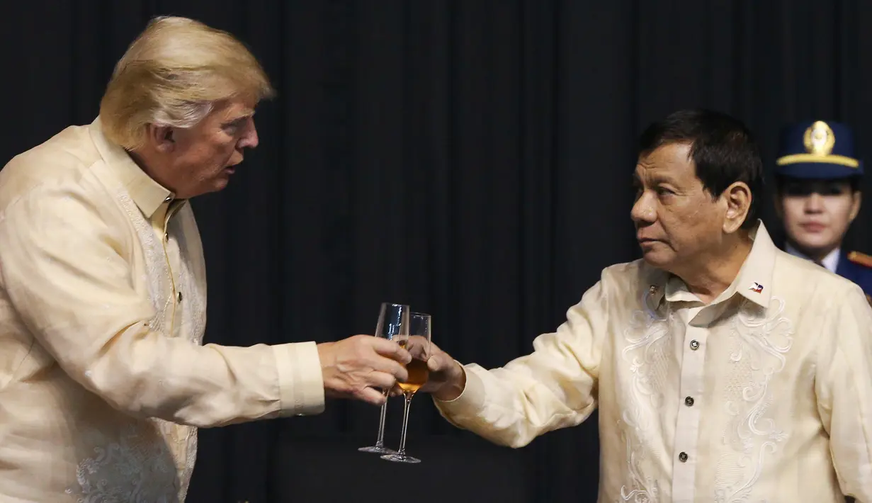 Presiden AS, Donald Trump bersulang dengan Presiden Filipina, Rodrigo Duterte dalam acara makan malam bersama konferensi ASEAN ke-31 di Manila, Minggu (12/11). Trump mengenakan pakaian resmi Filipina yaitu Barong Tagalog. (Athit Perawongmetha/Pool via AP)