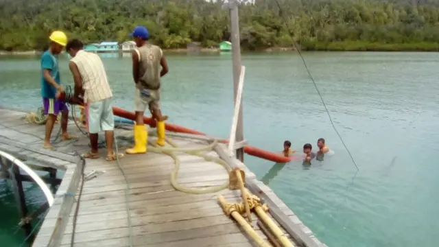 Karyawan PT PLN (Persero) bergotong-rotong mengangkat tiang yang akan digunakan untuk penyangga kabel listrik di Natuna, Kepulauan Riau. (Foto: Humas PLN)