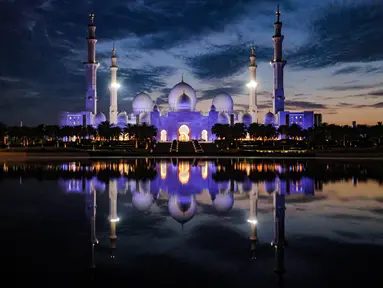 Masjid Agung Sheikh Zayed menyala saat matahari terbenam di Abu Dhabi selama Laylat al-Qadr, salah satu malam paling suci selama bulan puasa Ramadhan pada 17 April 2023. (Photo by Karim SAHIB / AFP)