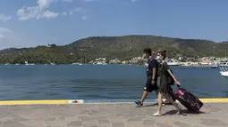 Pengunjung mengenakan masker terlihat di pelabuhan Pulau Poros, Yunani (7/8/2020). Terus bertambahnya jumlah kasus terkonfirmasi coronavirus di beberapa wilayah Yunani memaksa pihak berwenang memberlakukan jam malam pertama selama musim pariwisata di Pulau Poros. (Xinhua/Marios Lolos)