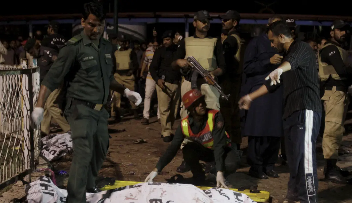 Petugas menutupi korban tewas ledakan bom dengan kain di area parkir taman Gulshan e Iqbal Park di Lahore, Pakistan, (27/3/2016). Korban tewas akibat ledakan bom tersebut mencapai sekitar 69 orang. (REUTERS/Mohsin Raza)
