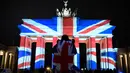 Pengunjung mengamati gerbang bersejarah Brandenburg yang diterangi dengan warna bendera kebangsaan Inggris sebagai bentuk turut berduka cita atas teror London yang menewaskan lima orang, di ibu kota Jerman, Berlin, Kamis (23/3). (Tobias SCHWARZ/AFP)