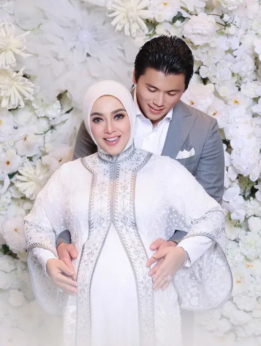 Syahrini memadukan penampilannya dengan hijab putih polos. Reino sendiri tampil gentleman mengenakan setelan jas dan celana panjang abu-abu, serta kemeja putih polos di baliknya. [Foto: Instagram/princessyahrini]