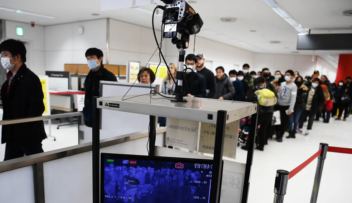 Penumpang yang tiba dengan salah satu penerbangan terakhir dari kota Wuhan China berjalan melalui stasiun pemeriksaan kesehatan di bandara Narita di prefektur Chiba, di luar Tokyo (23/1/2020). (AFP Photo/Charly Triballeau)