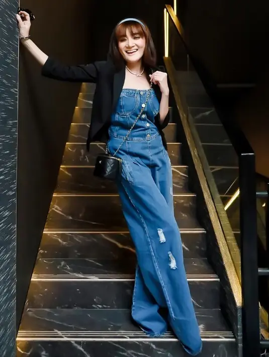 Jumpsuit denim yang dipadukan dengan blazer hitam membuat penampilannya terlihat bak ABG. Dirinya juga memilih menggunakan bandana berwarna biru serta sling bag hitam untuk menyempurnakan penampilannya. (Liputan6.com/IG/@kikiamaliaworld)