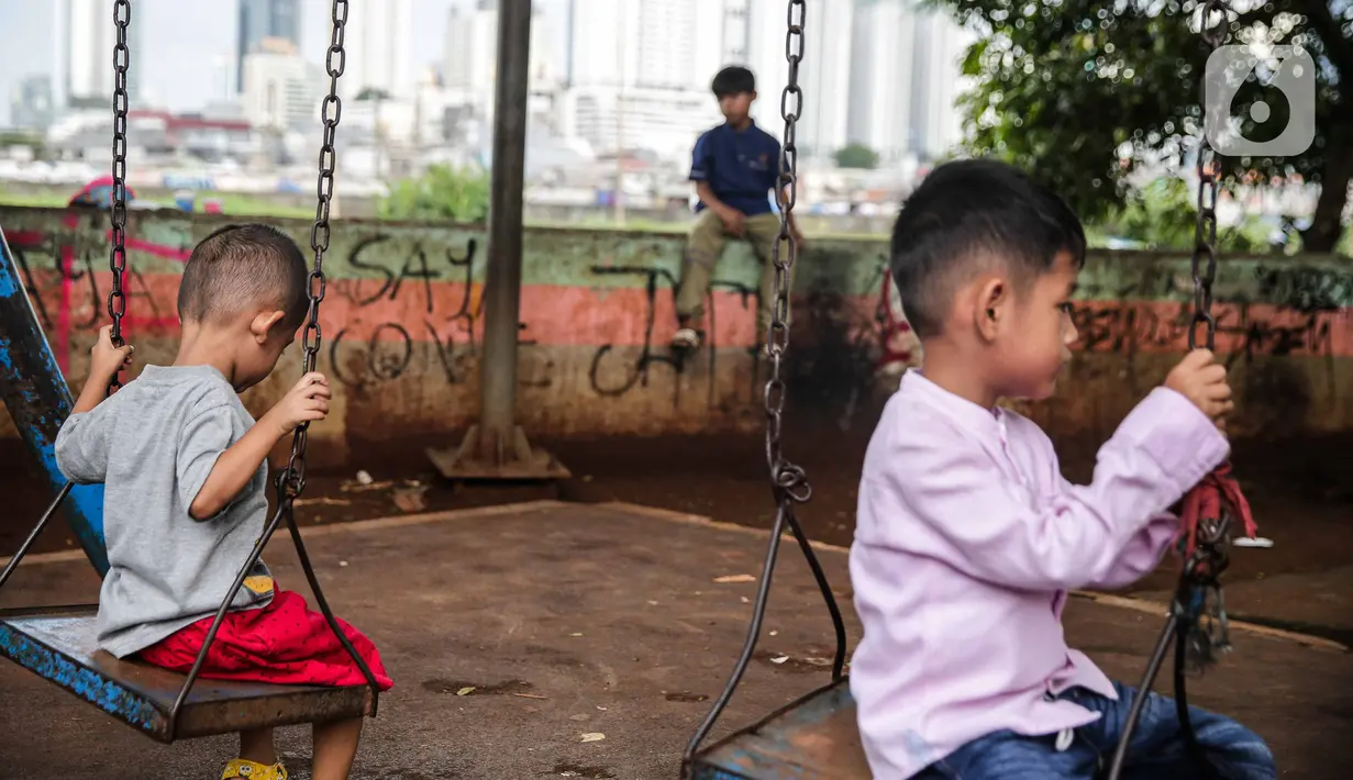 Sejumlah anak bermain di taman bermain yang terdapat di Bantaran Banjir Kanal Barat Kawasan Petamburan, Jakarta, Minggu (12/12/2021). Minimnya taman bermain di pemukiman padat penduduk membuat anak-anak seringkali bermain di tempat yang tidak semestinya. (Liputan6.com/Faizal Fanani)