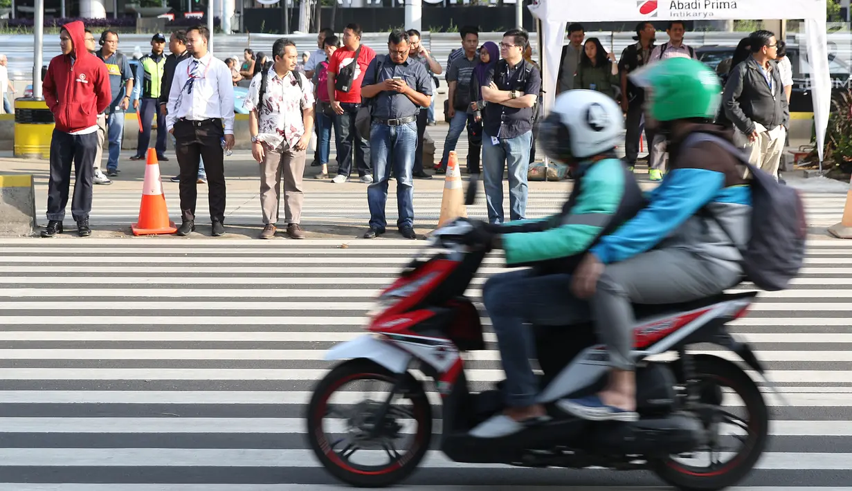 Warga bersiap melintasi Pelican Crossing di sekitar Halte Transjakarta GBK, Jakarta, Jumat, (30/11). Penyeberangan pelican crossing diberlakukan selama revitalisasi jembatan penyeberangan orang (JPO) berlangsung. (Liputan6.com/Helmi Fithriansyah)