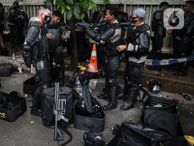 Personel Brimob bersiap mengenakan perlengkapan pelindung diri di Kawasan Bundaran HI, Jakarta, Selasa (13/10/2020). Sebanyak kurang lebih 12 ribu personel gabungan TNI, Polri dan Pemprov DKI Jakarta diterjunkan mengawal aksi tolak Undang-Undang Cipta Kerja Omnibus Law. (Liputan6.com/Faizal Fanani)