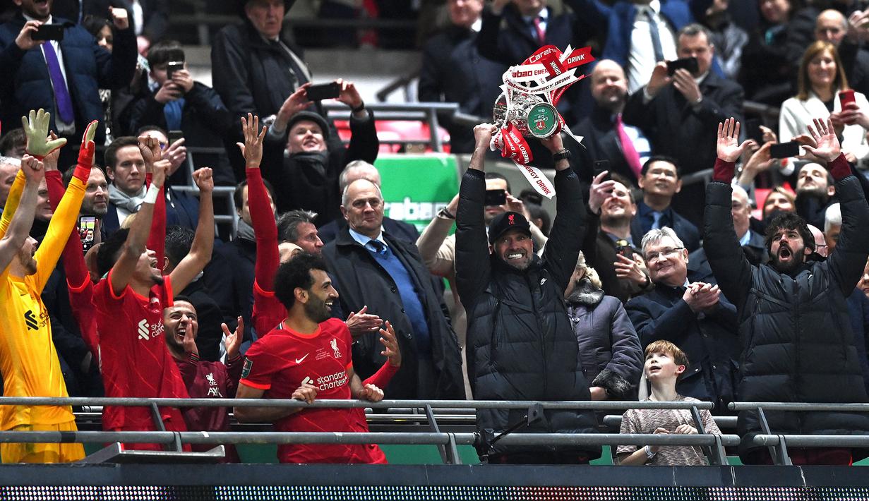 Pelatih Liverpool, Jurgen Klopp mengangkat trofi Carabao Cup 2021/2022 setelah mengelahkan Chelsea pada laga final yang berlangsung di Wembley Stadium, London, 27 Februari 2022. The Reds menang pada babak penalti dengan skor 11-10. Ini merupakan gelar Carabao Cup ke-9 bagi klub yang berkandang di Anfield tersebut. (AFP/Glyn Kirk)