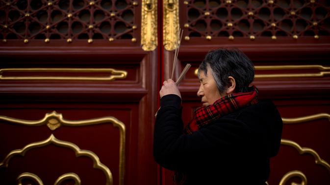 Seorang wanita memegang dupa berdoa di Kuil Lama di Beijing (5/2). Orang-orang China merayakan hari pertama Tahun Baru Imlek pada hari Selasa, Tahun Babi di zodiak Tiongkok dengan berdoa di kuil. (AP Photo/Mark Schiefelbein)