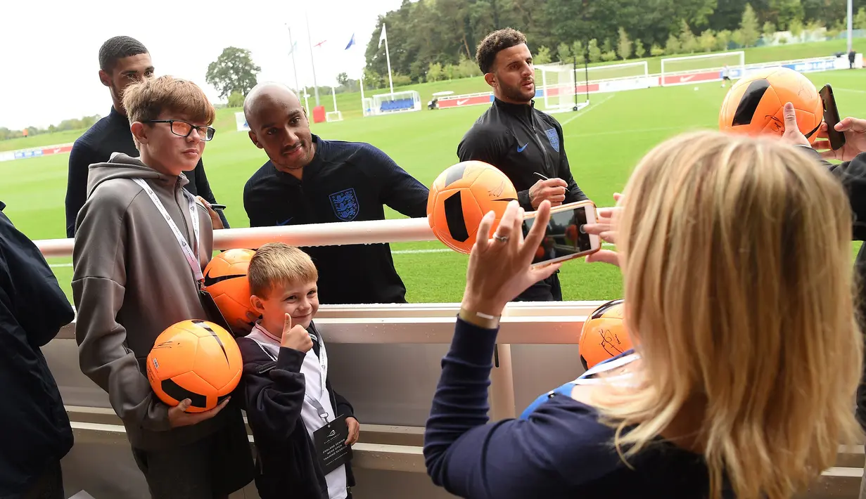 Gelandang Inggris Fabian Delph (kedua kiri) dan bek Kyle Walker (tengah) berpose dengan penggemar saat latihan jelang menghadapi Spanyol di St George's Park di Burton-on-Trent, Inggris tengah, (4/9). (AFP Photo/Paul Ellis)