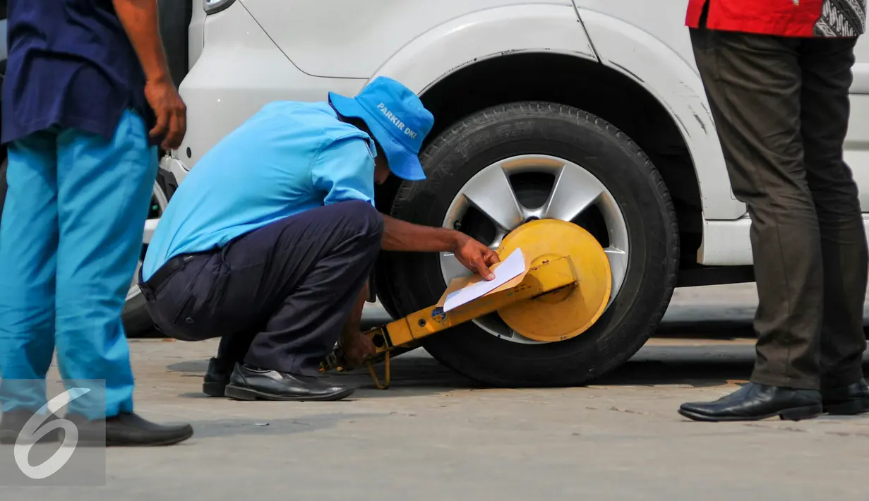 Petugas menggembok ban mobi hasil razia parkir di lahan Parkir IRTI Monas, Jakarta Pusat, Rabu (20/5). Total retribusi yang didapat Dishub DKI dari penderekan parkir liar mulai mencapai hampir Rp 4 miliar. (Liputan6.com/Yoppy Renato)