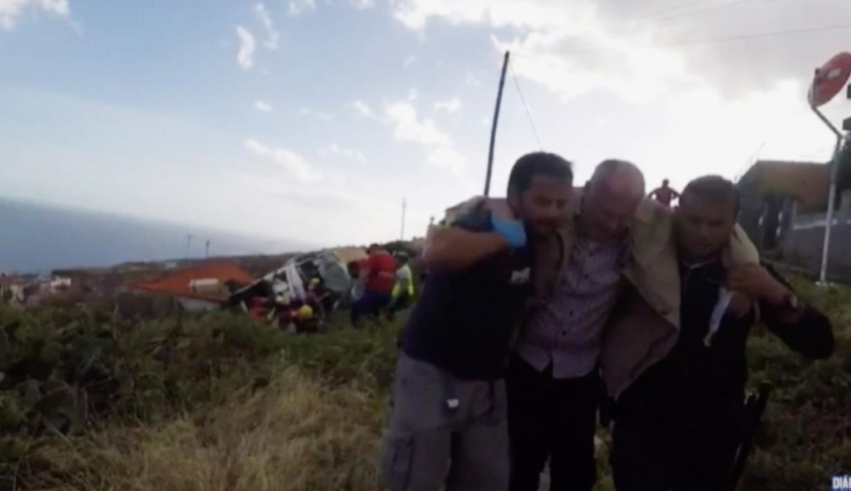 Petugas penyelamat mengevakuasi korban kecelakaan sebuah bus pariwisata yang terguling di Kota Canico, Pulau Madeira, Portugal, Rabu (17/4). Polisi setempat menyatakan belum mengetahui apakah ada korban tewas selain penumpang bus. (TVI via AP)