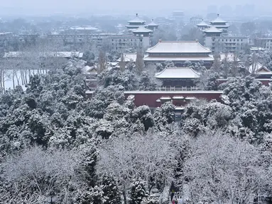 Sejumlah pengunjung (bawah) saat mengunjungi taman di dekat Kota Terlarang setelah salju turun di Beijing (30/11/2019). Beijing mengalami hujan salju pertama di seluruh kota sejak awal musim dingin dari 29 hingga 30 November 2019. (AFP Photo/Wang Zhao)