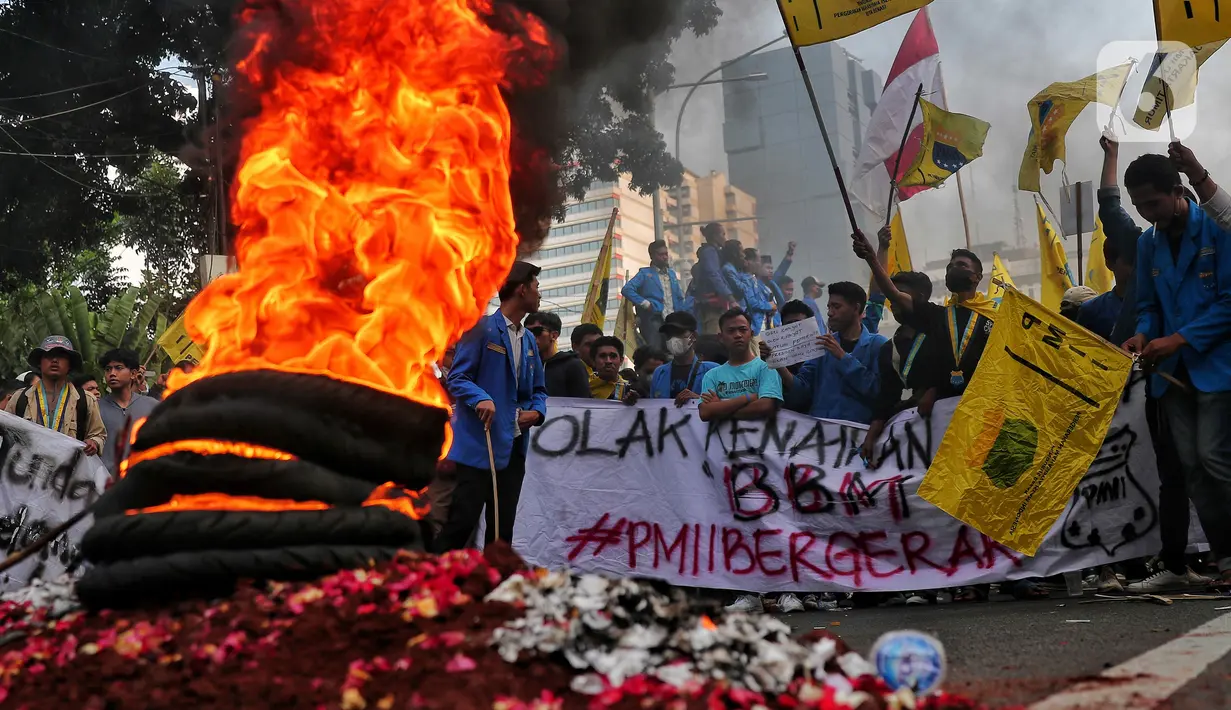Mahasiswa membakar ban bekas saat aksi unjuk rasa atau demo BBM naik di kawasan Patung Kuda, Jakarta, Senin (5/9/2022). Mereka datang membawa atribut bendera organisasi hingga spanduk tuntutan menolak kenaikan BBM. (Liputan6.com/Angga Yuniar)