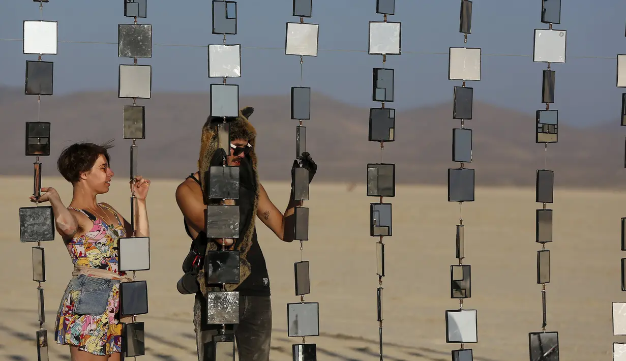 Denise S (kiri) dan Richard S. melihat pameran seni dalam festival festival Burning Man 2015 di Gurun Black Rock, Nevada, (31/9/2015). Partisipan dari seluruh dunia hadiri festival seni unik ini selama sepekan. (REUTERS/Jim Urquhart)