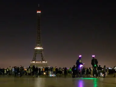 Pengunjung berkumpul di alun-alun Trocadero saat lampu Menara Eiffel di Paris, dipadamkan, Rabu (24/5) dini hari. Hal itu sebagai bentuk penghormatan dan duka cita atas serangan bom pada konser Ariana Grande di Manchester, Inggris (AP Photo/Francois Mori)