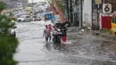Pengendara mendorong motornya menerobos banjir yang menggenangi Jalan Arif Rahman Hakim di Depok, Jawa Barat, Senin (18/5/2020). Sistem drainase buruk menjadi penyebab utama kawasan tersebut selalu tergenang banjir setiap hujan deras. (Liputan6.com/Immanuel Antonius)
