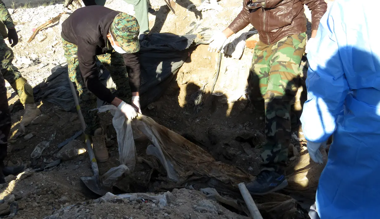 Polisi Irak mengumpulkan jasad korban kesadisan kelompok ISIS di sebuah kuburan massal yang ditemukan di Kota Ramadi, sebelah barat Baghdad, Selasa (26/1). Kuburan massal tersebut berisi sisa-sisa sekitar 40 jasad. (AFP/ MOADH AL-DULAIMI)
