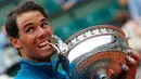Petenis Spanyol, Rafael Nadal menggigit pialanya setelah mengalahkan Dominic Thien dari Austria pada partai final Prancis Terbuka di Stadion Roland Garros, Minggu (10/6). Ini merupakan trofi ke-11 Prancis Terbuka yang diraih Nadal. (AP/Michel Euler)