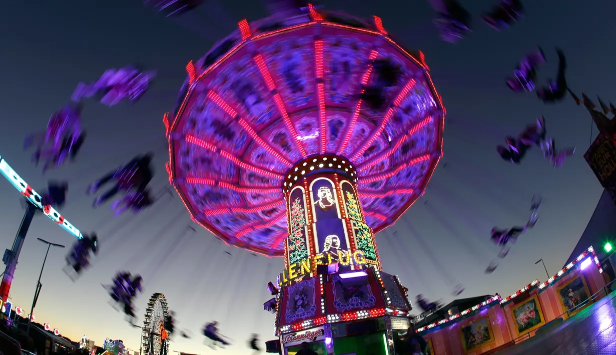 Pengunjung menikmati wahana ayunan ontang-anting saat berlangsungnya festival bir Oktoberfest di Munich, 27 September 2018. Oktoberfest adalah rangkaian festival terbesar di dunia yang diadakan setiap tahun oleh masyarakat Jerman. (AP/Matthias Schrader)