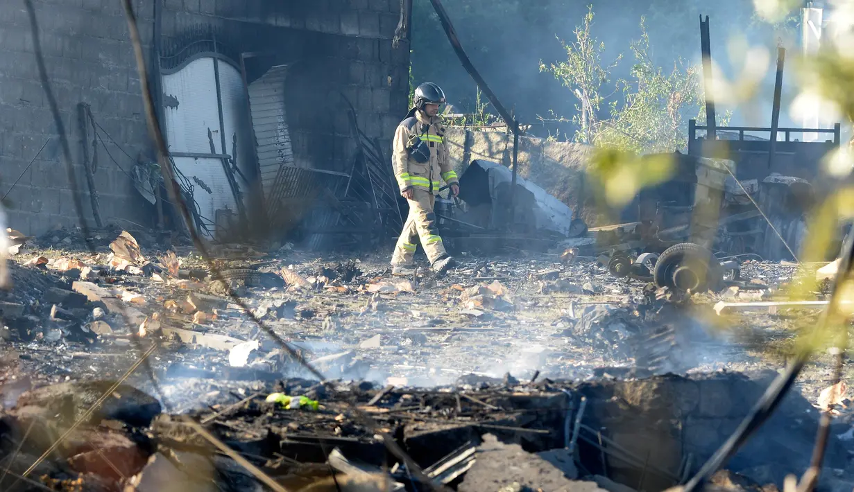 Petugas pemadam kebakaran memeriksa area yang terkena dampak ledakan gudang kembang api di Tui, Spanyol, Rabu (23/5). Satu orang tewas dalam kejadian tersebut. (MIGUEL RIOPA/AFP)