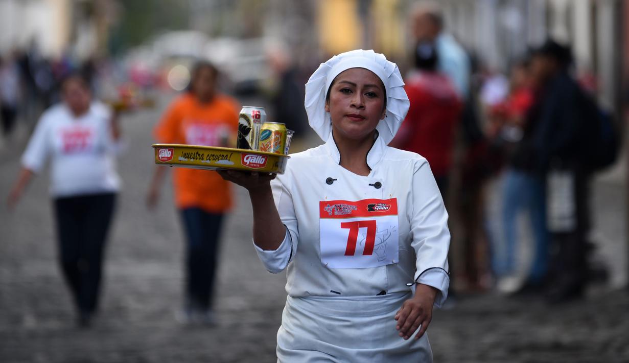 Seorang pramusaji membawa nampan dalam Waiters Race ke-16 di Antigua, barat daya Ibu Kota Guatemala City, Rabu (14/11). Ratusan peserta beradu kecepatan sembari membawa nampan berisi dua minuman ringan, bir dan air. (JOHAN ORDONEZ/AFP)