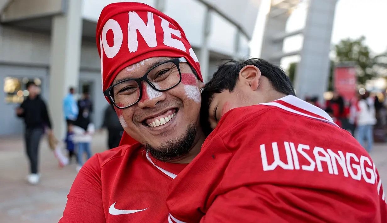Seorang suporter Indonesia menggendong sang anak untuk menyaksikan laga kedua Grup D Piala Asia 2023 antara Timnas Indonesia menghadapi Vietnam di Abdullah Bin Khalifa Stadium, Doha, Qatar, Jumat (19/1/2024). (AFP/Karim Jaafar)