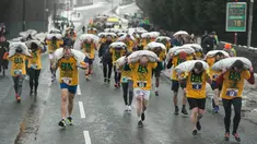 Peserta membawa karung berisi batu bara saat mengikuti World Coal Carrying Championships di Desa Gawthorpe, Wakefield, Inggris Utara, Senin (2/4). Kompetisi  tahunan mengakut karung batu bara ini dalam memperingati Senin Paskah. (OLI SCARFF/AFP)