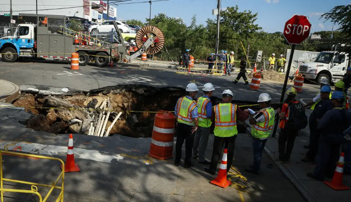 Sejumlah petugas saat menyelidiki sebuah lubang besar (sinkhole) di wilayah Brooklyn, New York, Selasa (4/8/2015). Lubang yang terbentuk di persimpangan pemukiman Sunset Park itu disebabkan erosi dan merusak pipa air serta aspal jalan. (AFP/Kena Betancur)