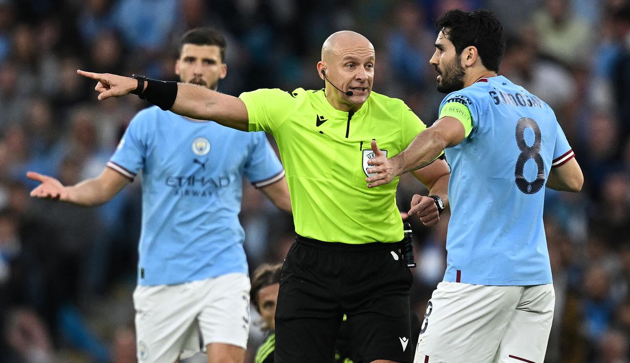 Wasit Szymon Marciniak berbicara dengan pemain Manchester City, Ilkay Gundogan pada laga leg kedua semifinal Liga Champions 2022/2023 antara Manchester City melawan Real Madrid di Etihad Stadium, Manchester, 17 Mei 2023. (AFP/Paul Ellis)
