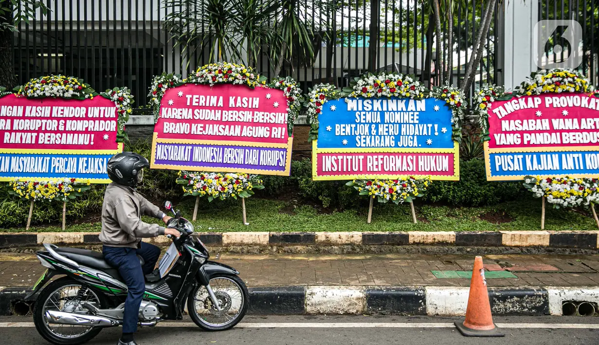 Pengendara melintasi karangan bunga di depan Gedung Kejaksaan Agung RI, Jakarta, Selasa (27/10/2020). Karangan bunga berasal dari korban terdampak kasus asuransi Jiwasraya yang mengharapkan kasus mega skandal itu bisa segera tuntas dan memberikan keadilan bagi mereka. (Liputan6.com/Faizal Fanani)