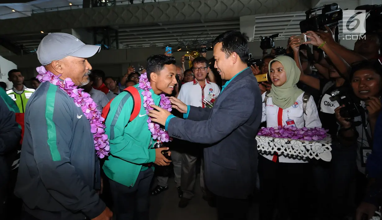 Menpora, Imam Nahrawi mengalungkan bunga kepada pemain Timnas Indonesia U-16, Fadillah Nur Rahman saat penyambutan di Bandara Soetta, Tangerang, Kamis (15/2). Timnas U-16 berhasil menjuarai turnamen Jenesys di Jepang. (Liputan6.com/Helmi Fithriansyah)