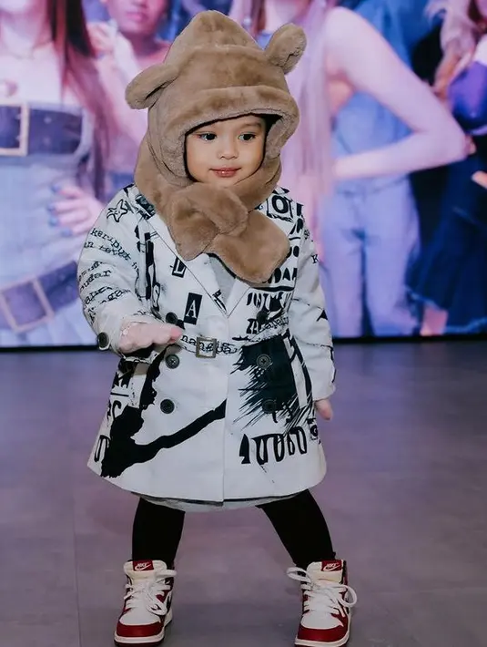 Ameena juga mengenakan jaket model blazer warna putih bercorak hitam dipadukan topi berbulu coklat, celana panjang hitam, dan sepatu Nikenya. [@aurelie.hermansyah]