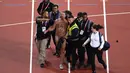 Petugas menangkap seorang pria tanpa busana dalam Kejuaraan Atletik Dunia London 2017 di Stadion London, London, (5/8). Pria ini berlari di Track Atletik London 2017 sebelum final kejuaraan atletik 100m putra. (AFP Photo/Antonin Thuillier)