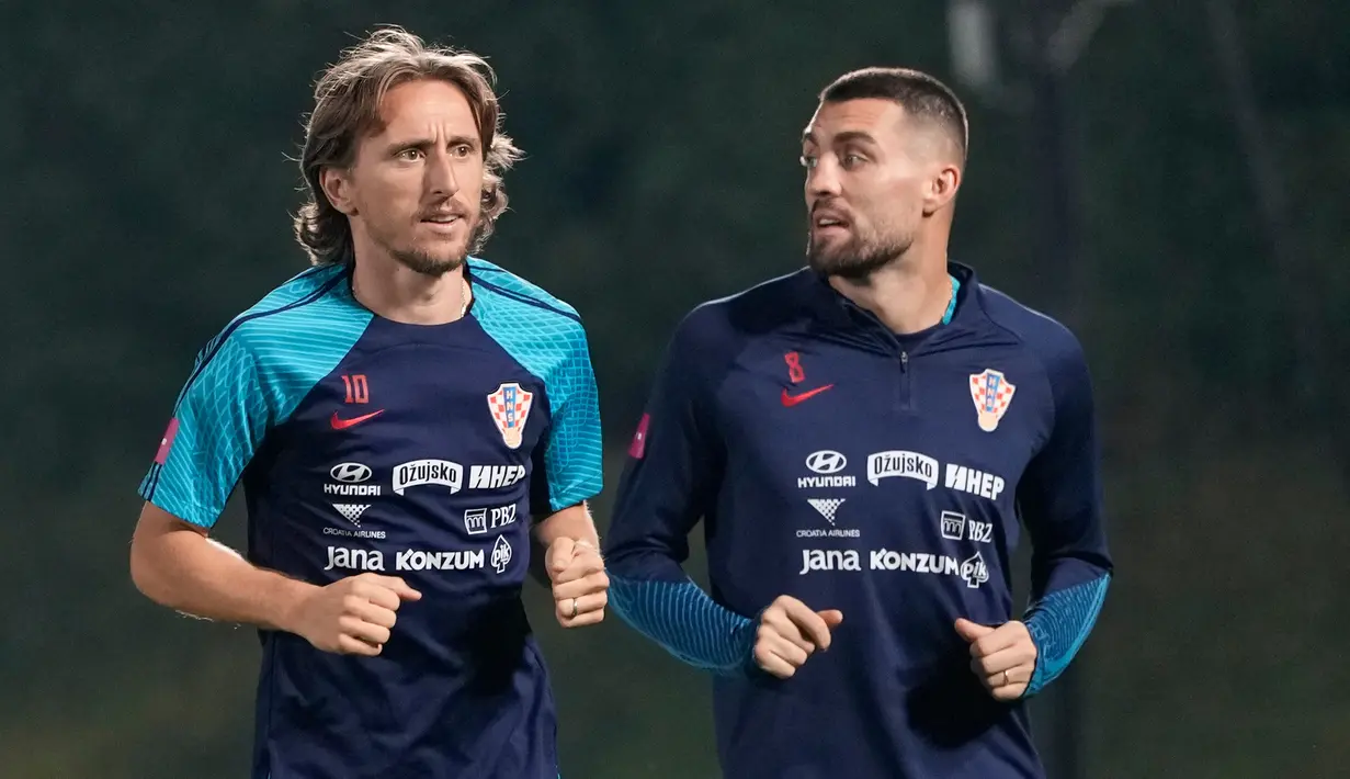 Pemain Kroasia Luka Modric (kiri) dan Mateo Kovacic sedang joging saat sesi latihan di Al Erssal Training Site 3, Doha, Qatar, Rabu (14/12/2022). Kroasia gugur saat mengalahkan Argentina di semi-final Piala Dunia 2022 dengan skor 0-3. (AP Photo/Andre Penner)
