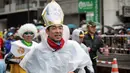 Seorang peserta mengenakan topi bergambar Paus Fransiskus selama mengikuti ajang Tokyo Marathon 2019 di Jepang, Minggu (3/3). Sebagian peserta tampil dengan mengenakan kostum unik seperti tokoh kartun. (AFP Photo/Behrouz Mehri)