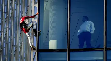 Alain Robert yang dikenal sebagai 'Spiderman Prancis' (kiri) memanjat gedung pencakar langit Skyper di pusat Frankfurt, Jerman, 23 November 2021. Alain Robert memanjat gedung setinggi 153 meter itu untuk meningkatkan kesadaran dunia tentang masalah perubahan iklim. (AP Photo/Michael Probst)