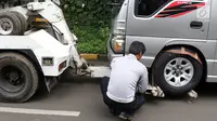 Petugas menderek dan menggembosi ban mobil yang parkir sembarangan di kawasan Tebet, Jakarta, Kamis (28/3). Meskipun berulang kali ditertibakan, namun masih banyak pengendara yang nekat parkir sembarangan sehingga mengganggu arus lalu lintas. (Liputan6.com/Immanuel Antonius)