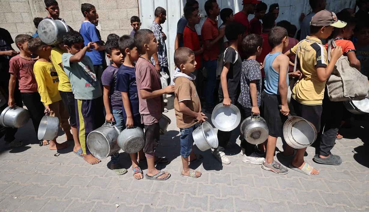Anak-anak Palestina mengantre untuk menerima makanan panas dari dapur amal kamp pengungsi Nuseirat di Jalur Gaza yang dikepung Israel pada 11 September 2025. (Eyad BABA/AFP)