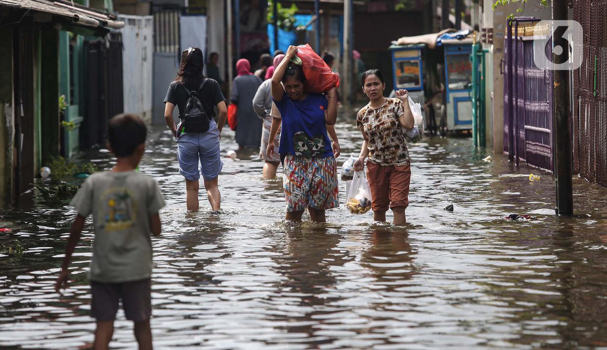 Warga melintasi banjir di salah satu permukiman penduduk di Kawasan Cengkareng Barat, Jakarta Barat, Kamis (30/1/2025). (Liputan6.com/Angga Yuniar)
