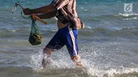 Warga berjalan membawa hasil tangkapan kerang di pesisir pantai Pulau Pasir, Lombok Timur, Sabtu (3/8/2019). Mereka mulai menangkap kerang ketika Pulau Pasir yang membentang laut akan tampak ketika air laut surut. (Liputan6.com/Fery Pradolo)