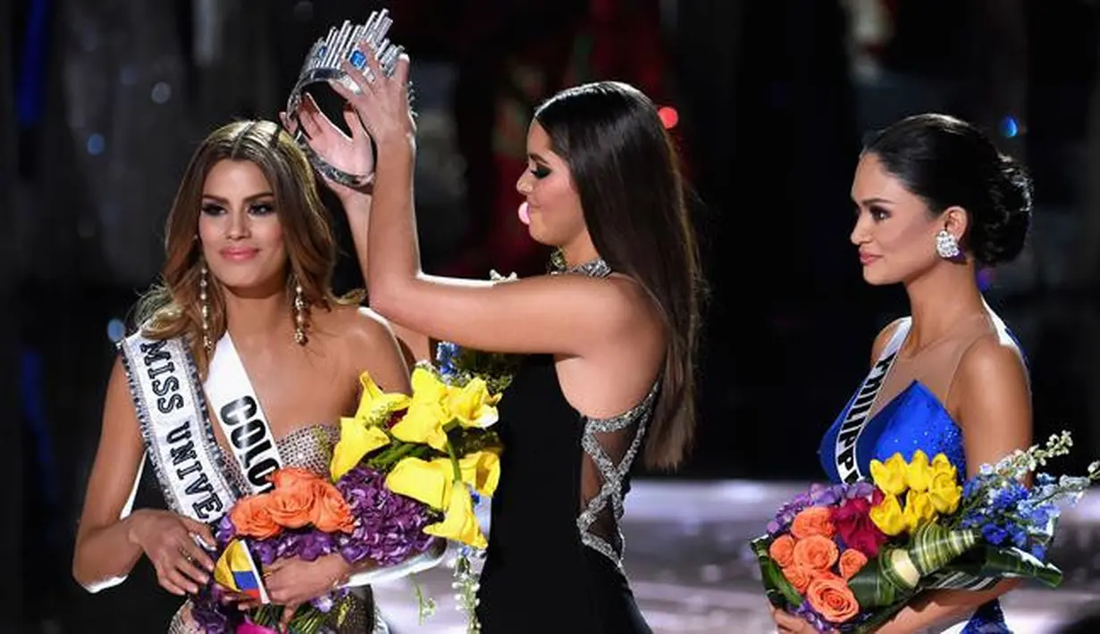Miss Universe 2014, Paulina Vega saat mengambil kembali mahkota yang sempat disematkan ke Miss Kolombia, untuk diberikan kepada Miss Universe 2015, Pia Alonzo Wurtzbach di The AXIS Las Vegas, AS, Minggu (20/12). (Ethan Miller/Getty Images/AFP)