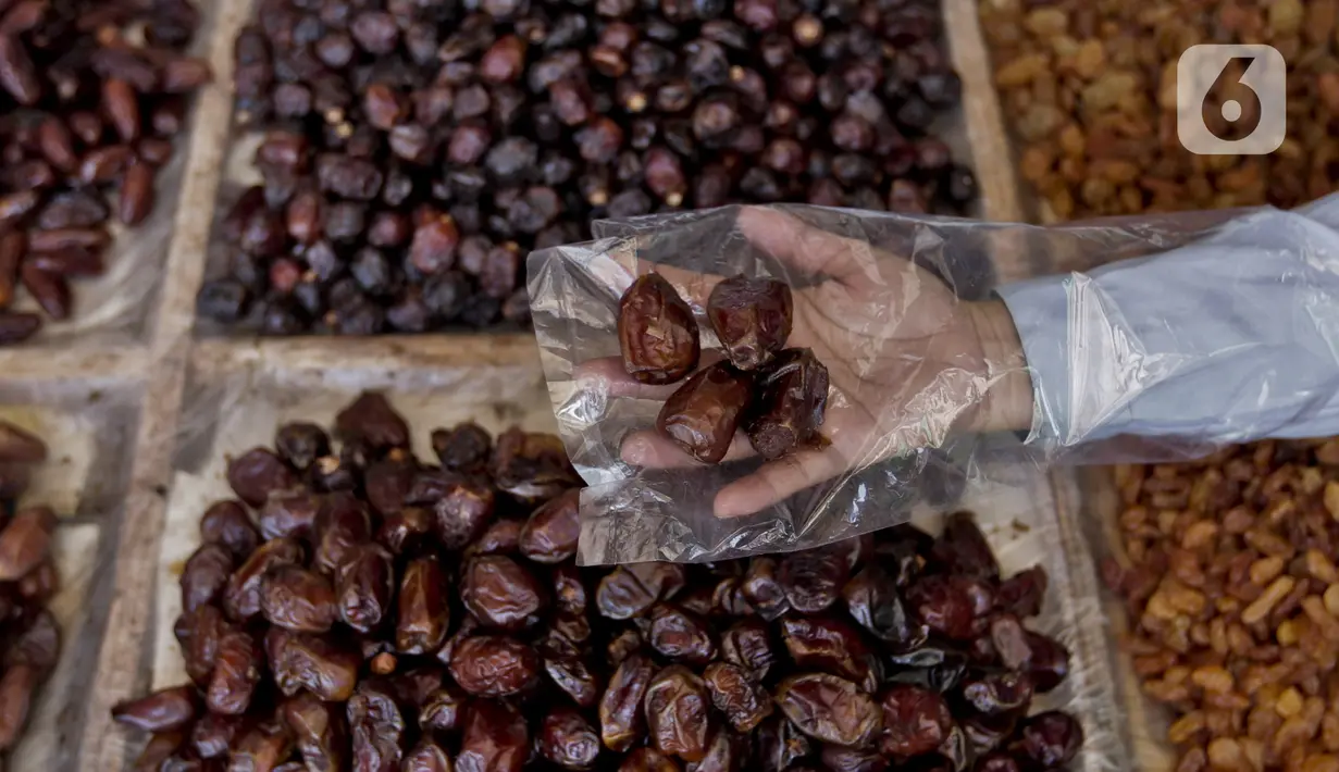 Pedagang menunjukkan kurma dagangannya di Pasar Tanah Abang, Jakarta, Rabu (22/4/2020). Pandemi COVID-19 membuat lesu penjualan kurma, keuntungan pedagang menurun hingga 80 persen lebih padahal pada tahun sebelumnya menjelang Ramadan biasanya ramai pembeli. (Liputan6.com/Johan Tallo)